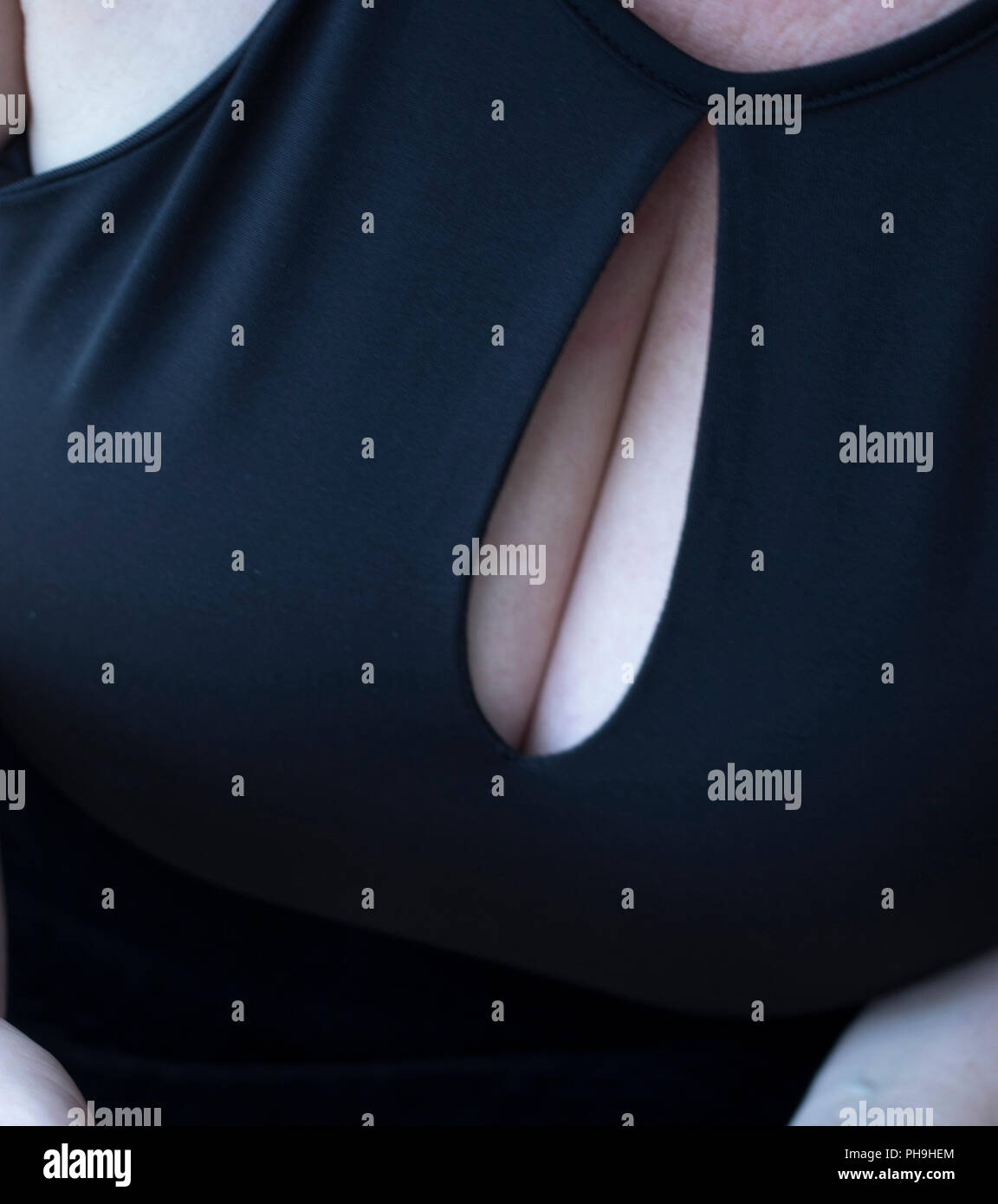 Sexy and sensual big bust curvy breasts woman in little black dress with low cut top showing boobs cleavage Stock Photo