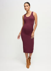 A pregnant woman wearing a fig-color textured bodycon maternity midi dress with tan suede boots